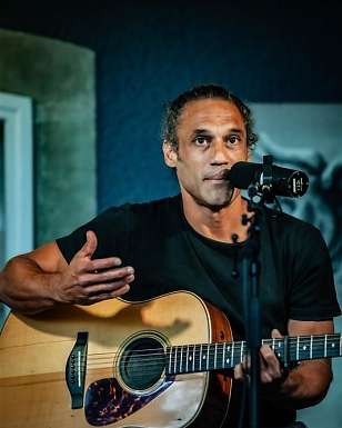 William White singt und spielt Gitarre bei einem Acoustic-Konzert mit Mikrofon