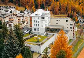 Sunstar Hotel Pontresina umgeben von dichten, goldgelben Lärchenwäldern im Herbst