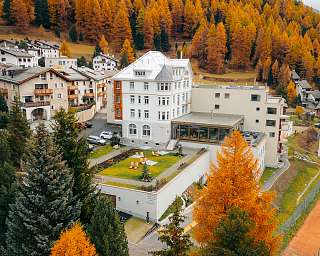 Luftaufnahme des Sunstar Hotels Pontresina umgeben von goldenen Lärchenwäldern im Herbst