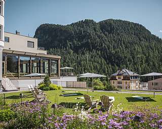 Sonniger Garten des Sunstar Hotels Pontresina mit Liegestühlen, blühenden Blumen und Bergkulisse im Sommer.