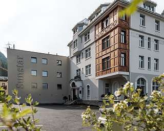 Aussenansicht des Sunstar Hotels Pontresina mit historischer Fassade, Innenhof und Blick durch Pflanzen im Vordergrund