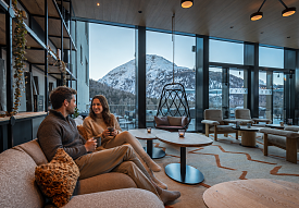 Paar geniesst warme Getränke in der Mountain Lounge mit Panoramablick auf schneebedeckte Berge