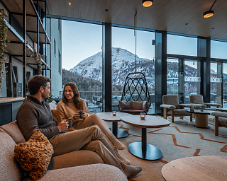 Paar entspannt bei Kaffee in der Mountain Lounge mit Blick auf verschneite Engadiner Berge