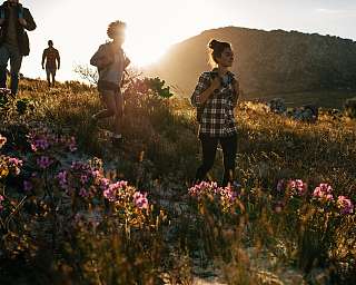 Wandergruppe auf einem Bergpfad in Pontresina bei Sonnenuntergang, umgeben von alpinen Blumen