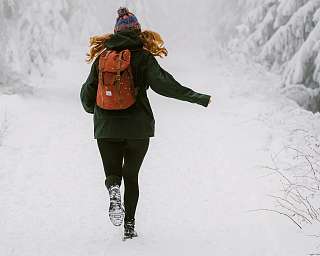 Frau auf einer Terrasse im Herbst schaut in die verschneiten Berge von Pontresina