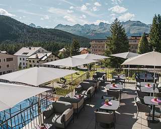 Sonnenterrasse des Sunstar Hotels Pontresina mit Sitzbereichen, Sonnenschirmen und Blick auf die Berglandschaft