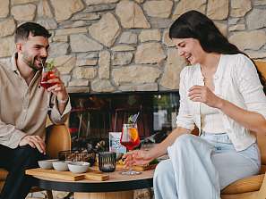 Paar stösst mit farbenfrohen Cocktails an und geniesst einen entspannten Moment im Sunstar Hotel Pontresina.